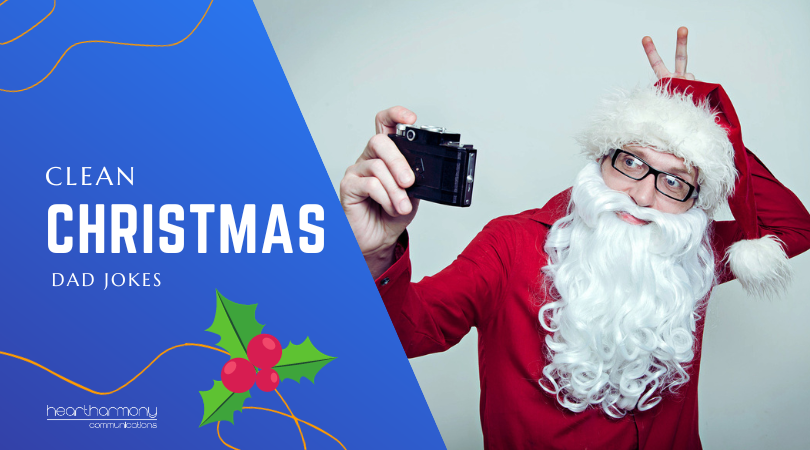 Man in a santa suit with his hand making bunny ears behind his head - while taking a selfie